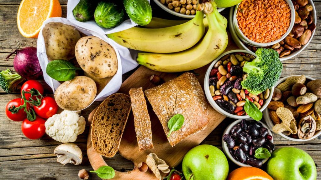 Diversos alimentos saudáveis, como frutas, legumes, sementes grãos e pão integral.