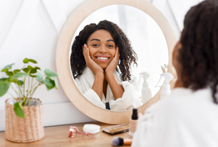 Mulher negra sorrindo em frente ao espelho