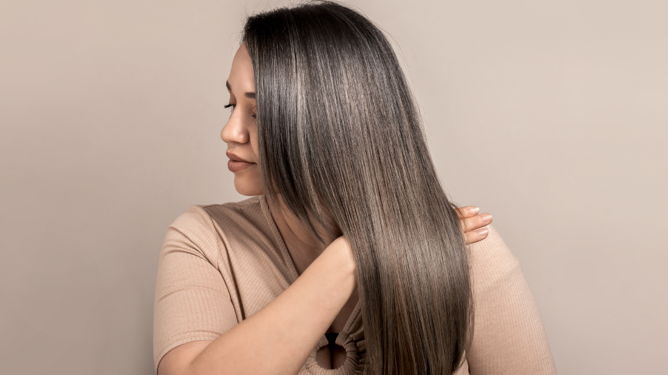 Como a biotina atua no crescimento capilar: mulher segurando os cabelos.