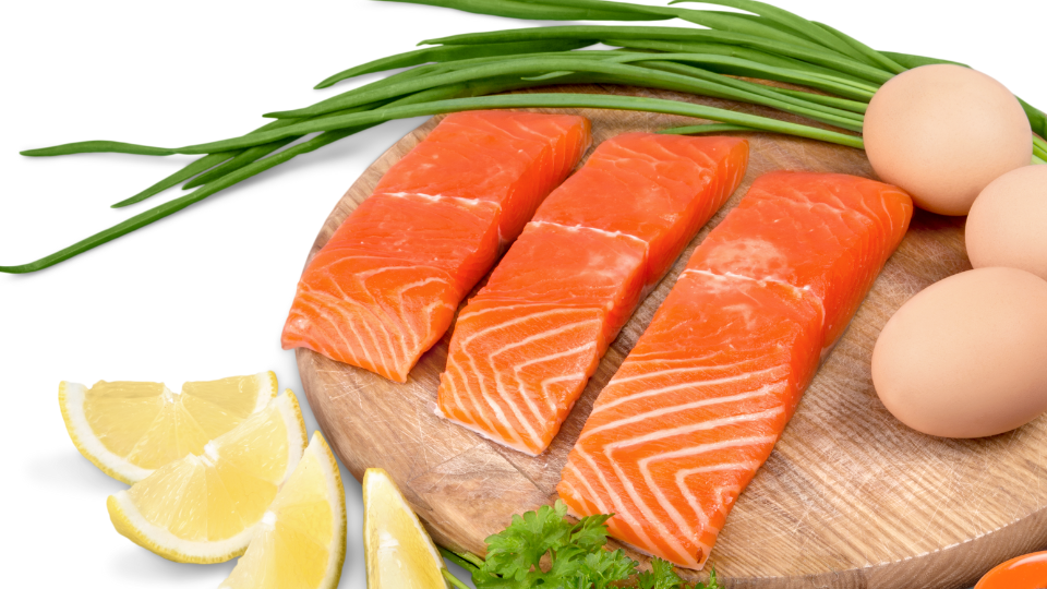 Tábua com salmão, ovos, vargem e limão para exemplificar alimentos ricos em proteínas.