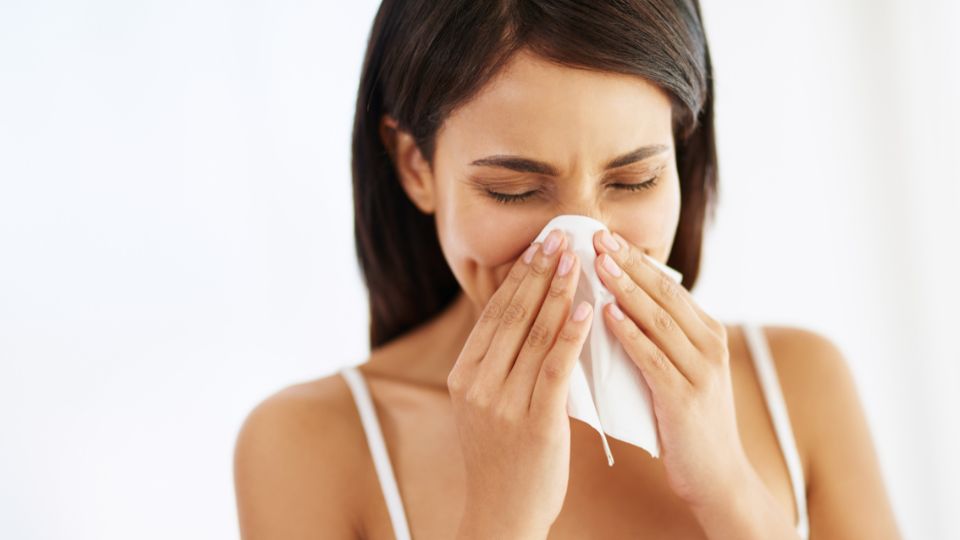 Mulher gripada com lenço no nariz.